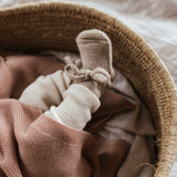 Babyfuss-in-Babyschuechen-mit-Schnuerbendel-in-Weidekorb-mit-weichen-Decken-zugedeckt